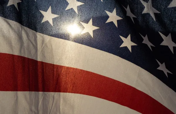 Closeup of waving American flag with light showing through it