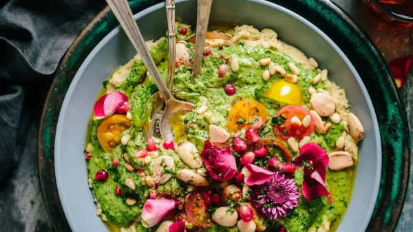 Colorful bowl of freshly prepared veggies, fruit and nuts with two vintage spoons in it